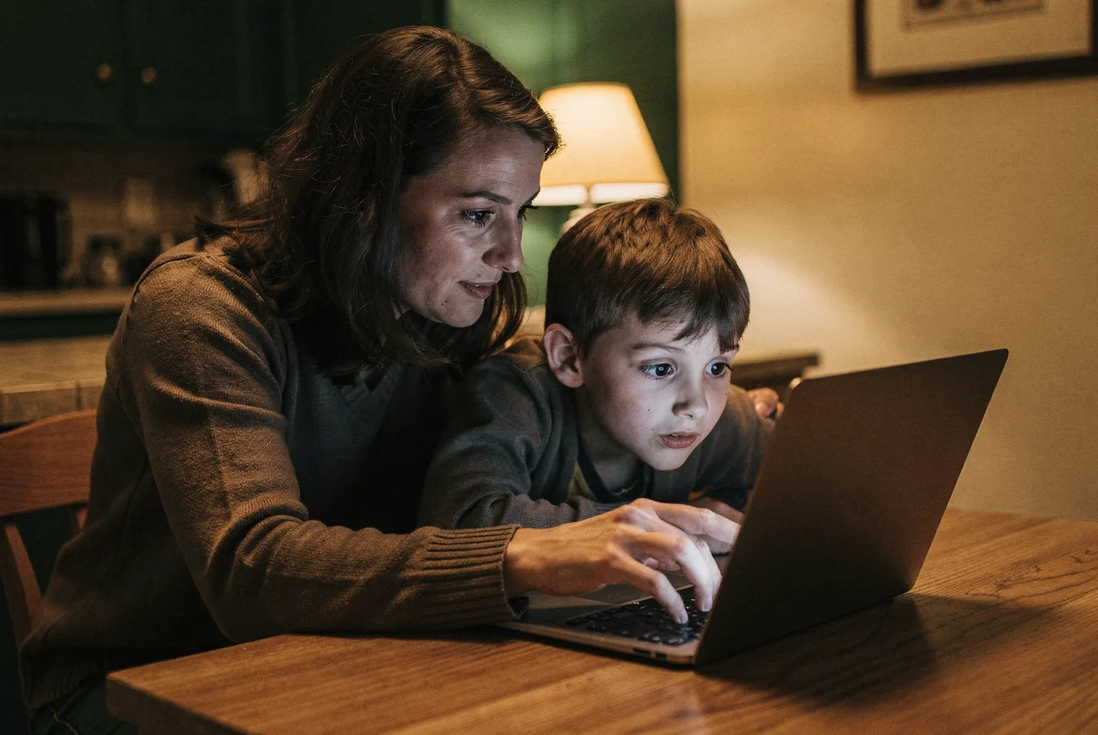 A parent and child reviewing school information together on a laptop at home